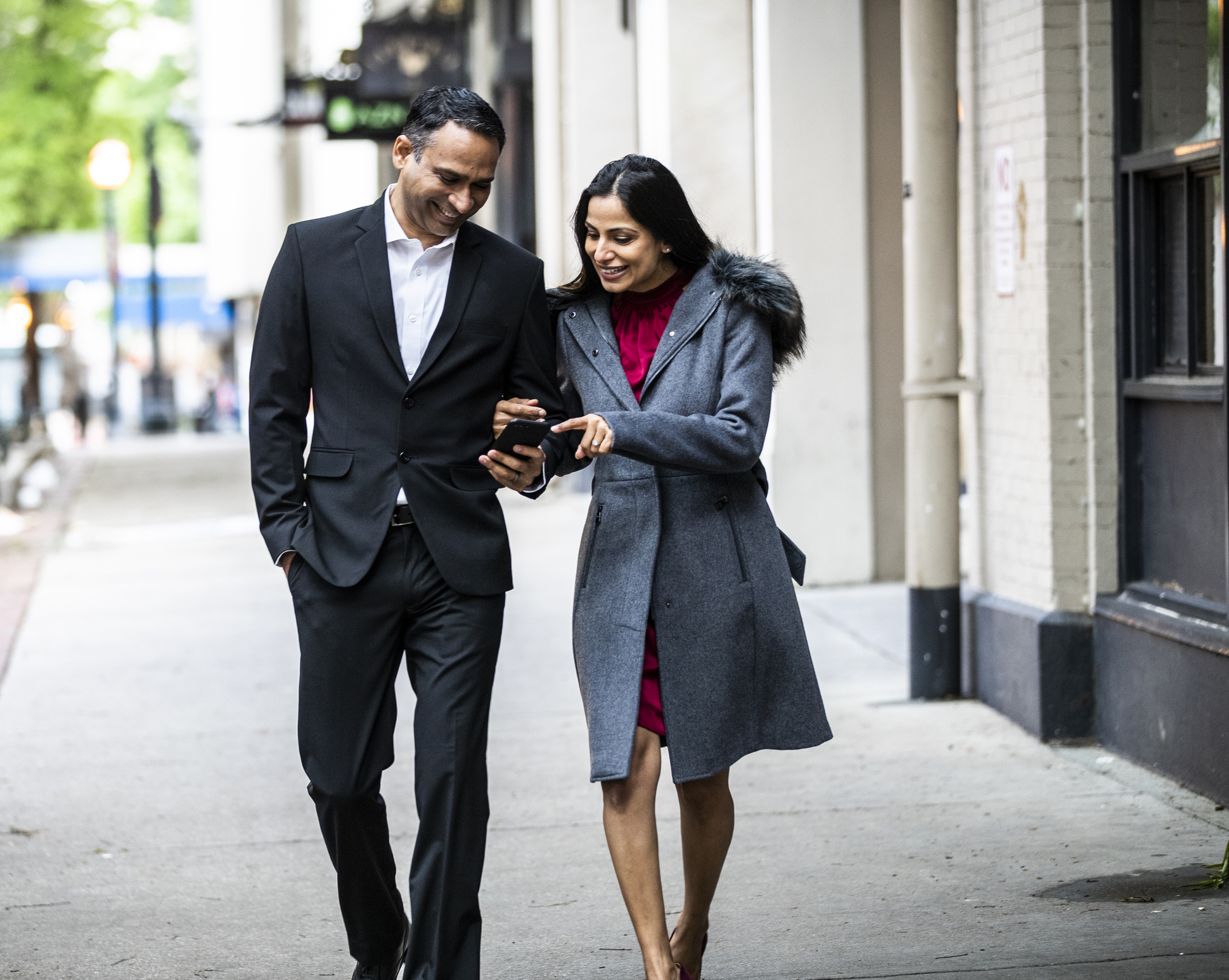 A couple walking and looking at a cell phone.