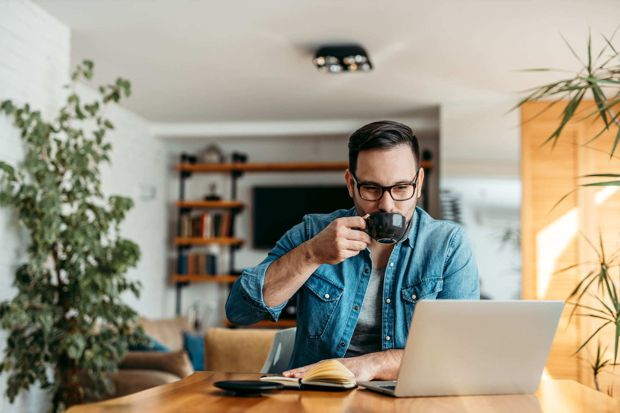Man drinking coffee while sitting at laptop.