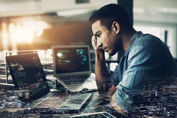 Person looking at stock charts on two laptops.