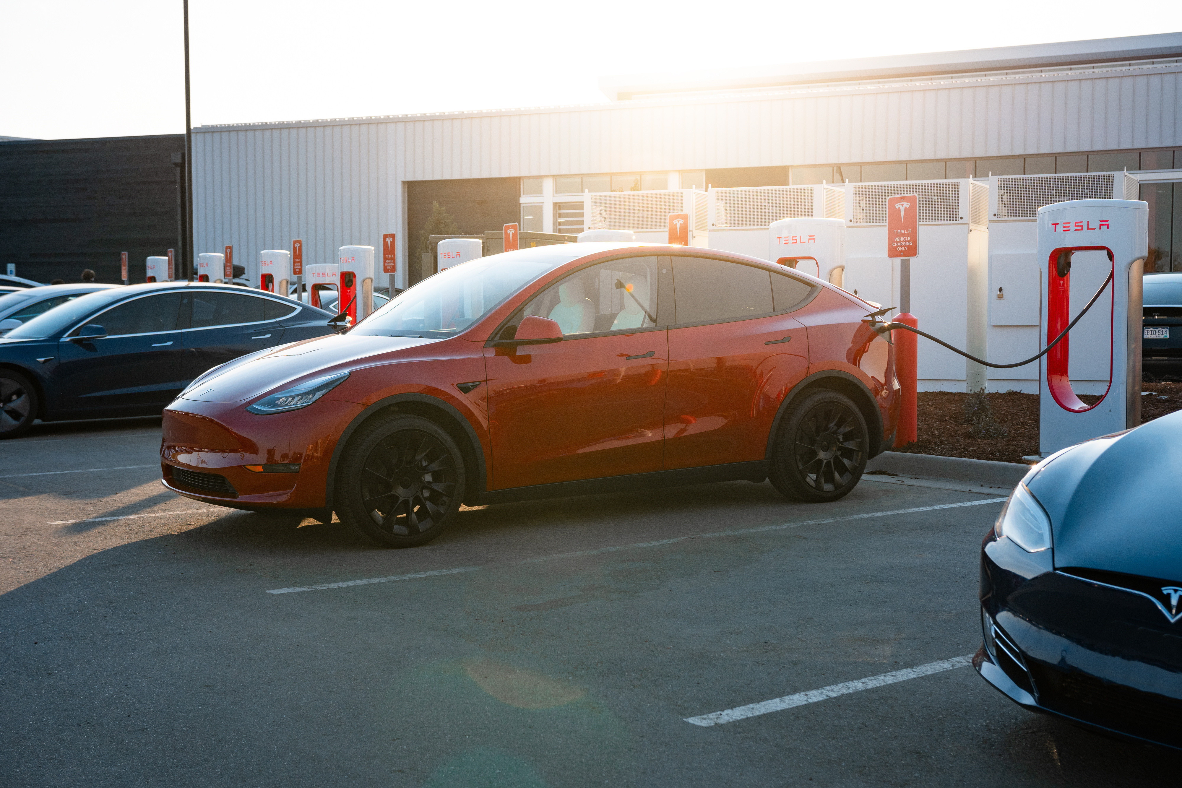 Red Tesla parked at Supercharger.