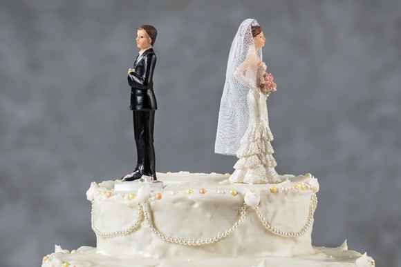 Wedding cake with figurines facing away from each other.