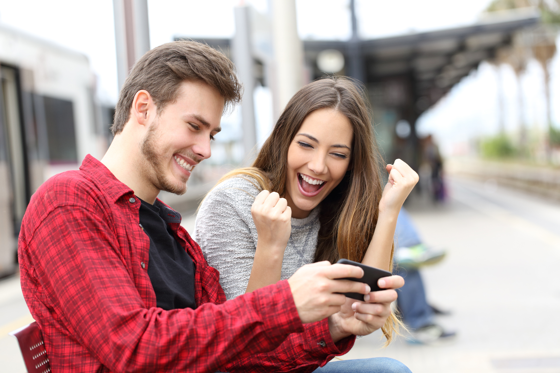 Two people smile at a shared smartphone.