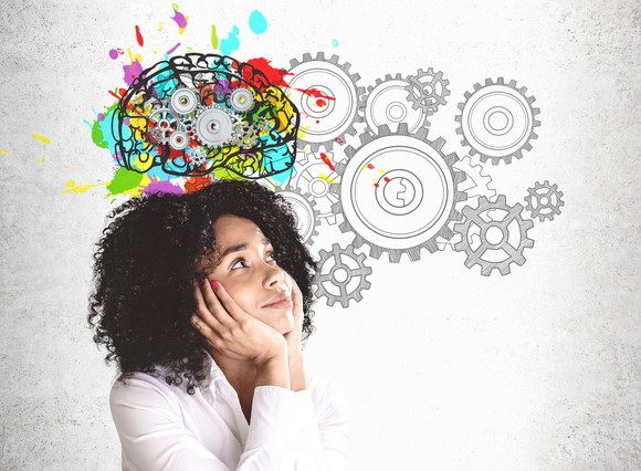A person looks up at a drawing of gears turning inside a brain.