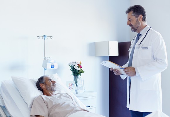 A doctor standing over a patient lying in bed.