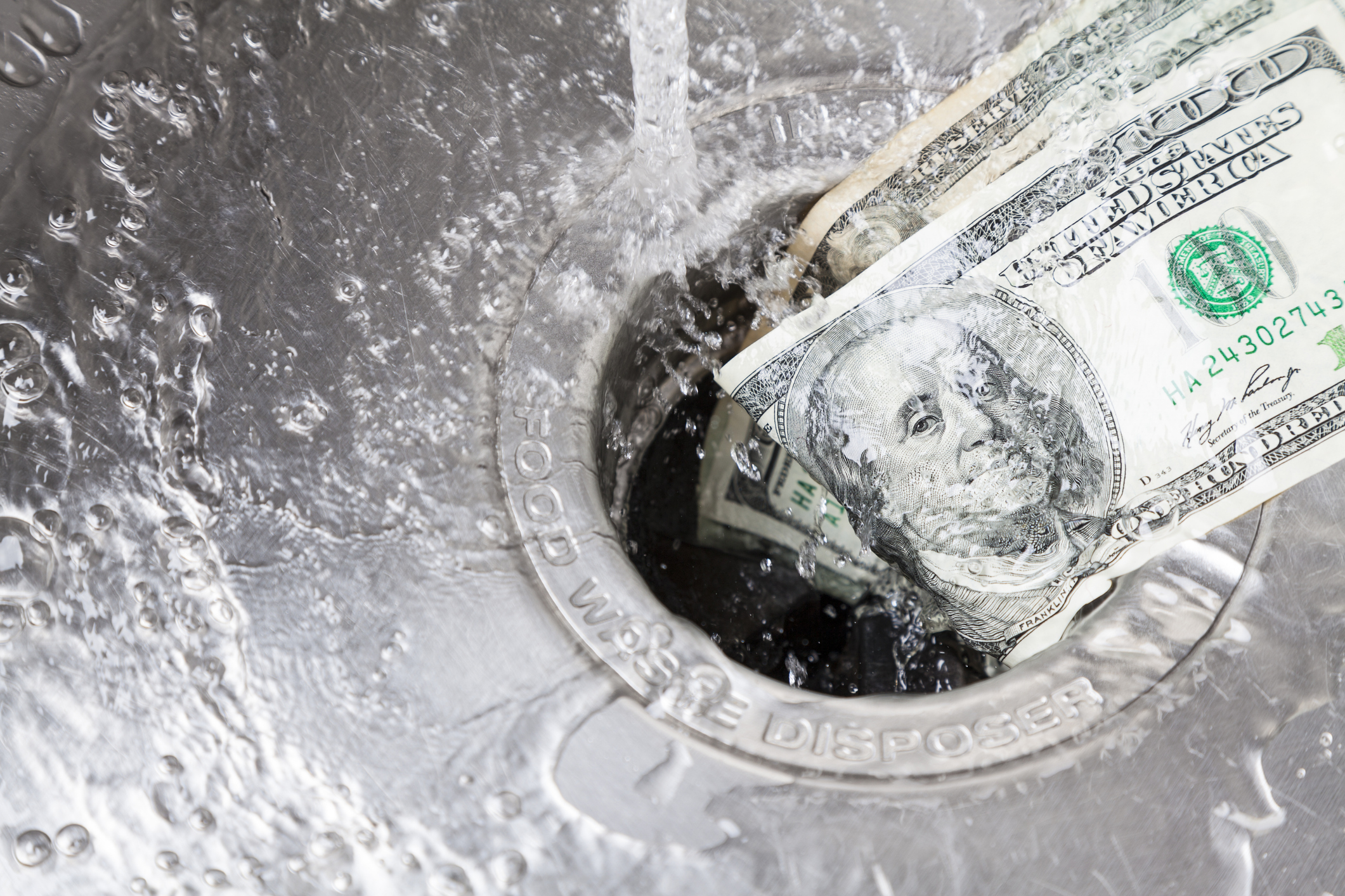 $100 bills being washed down the drain.