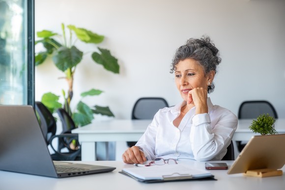 Person sitting at a table looking at a laptop.
