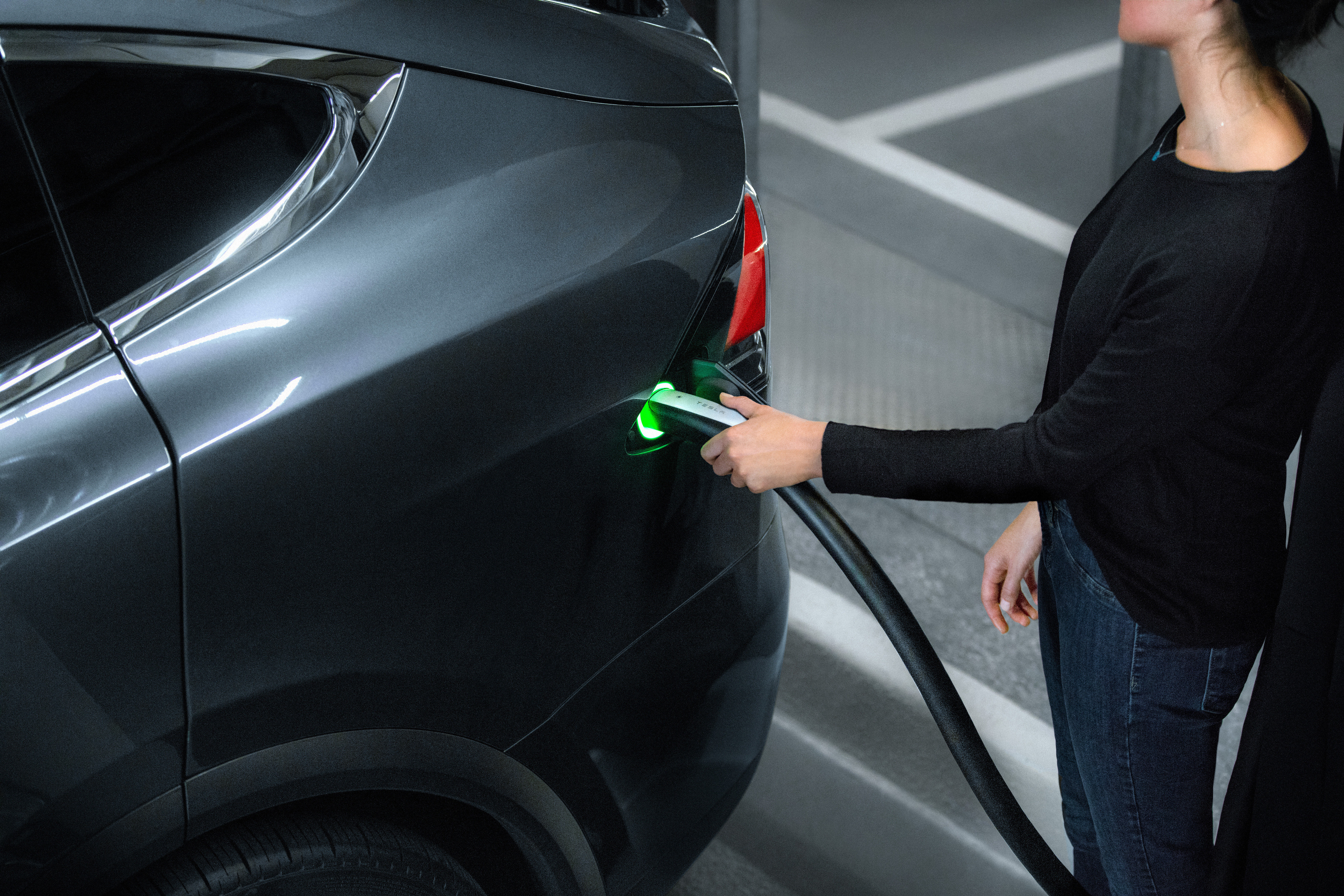 Tesla owner plugging charger in car.