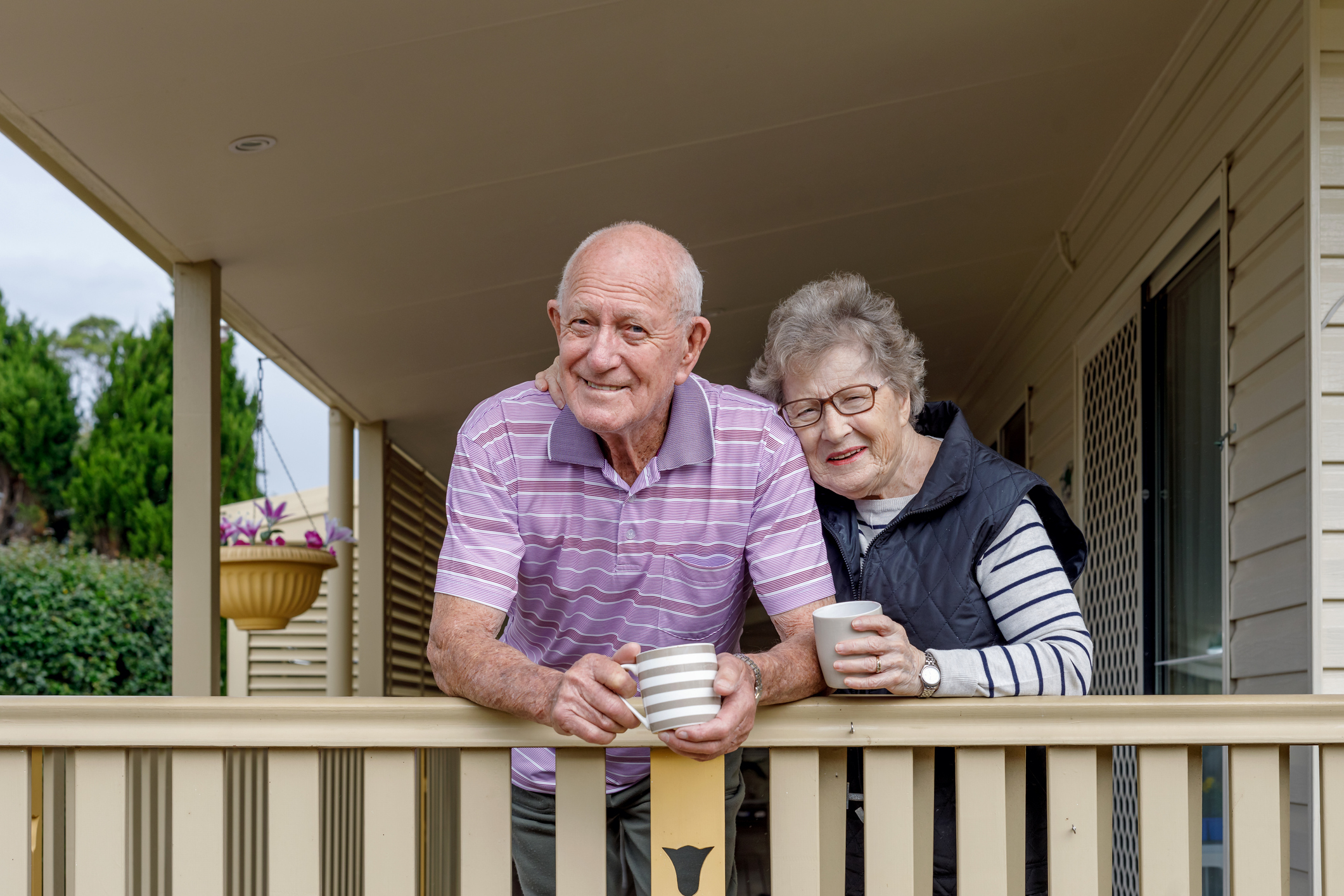 Two people on a deck holding coffee mugs.