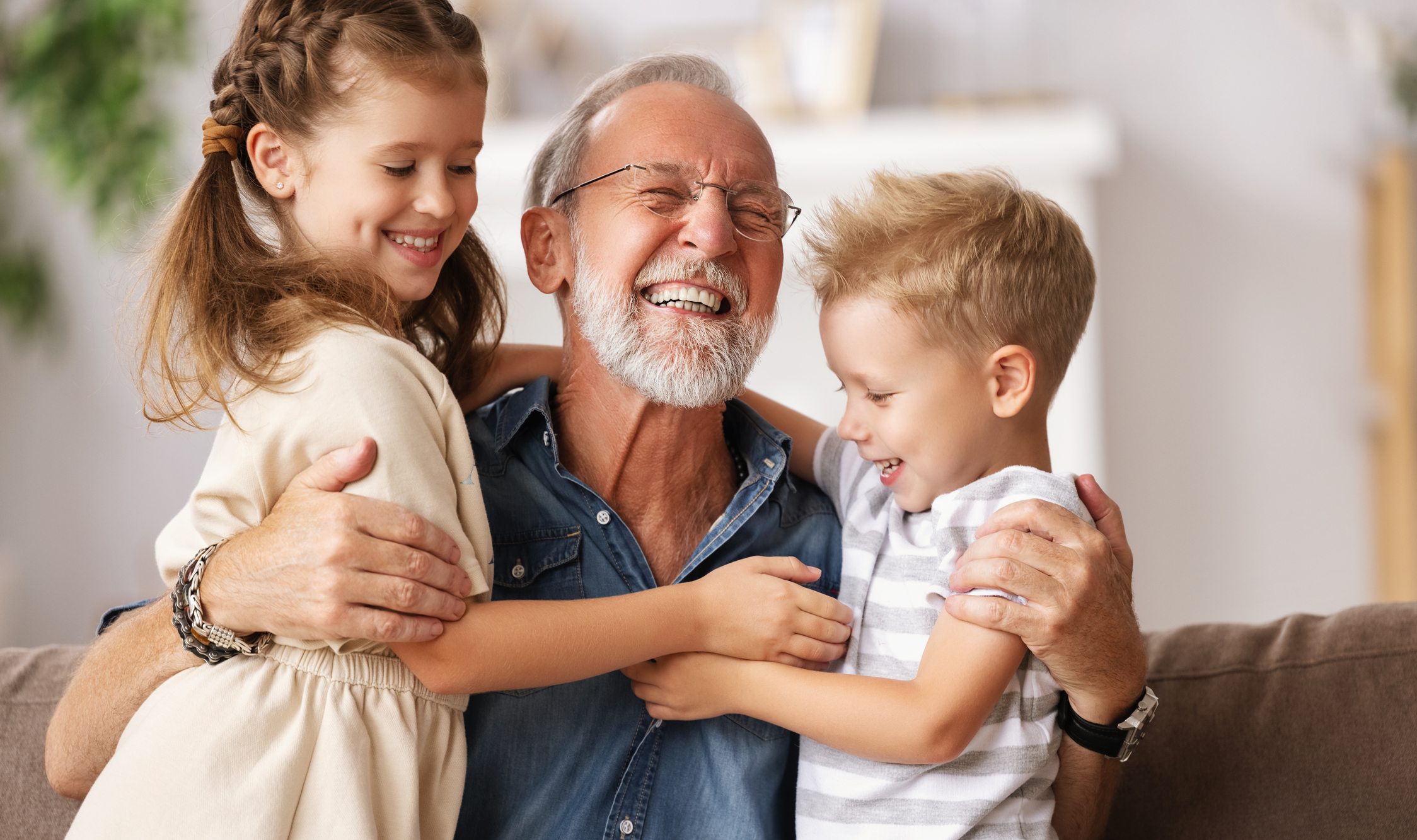 A person is hugging two young children and smiling.