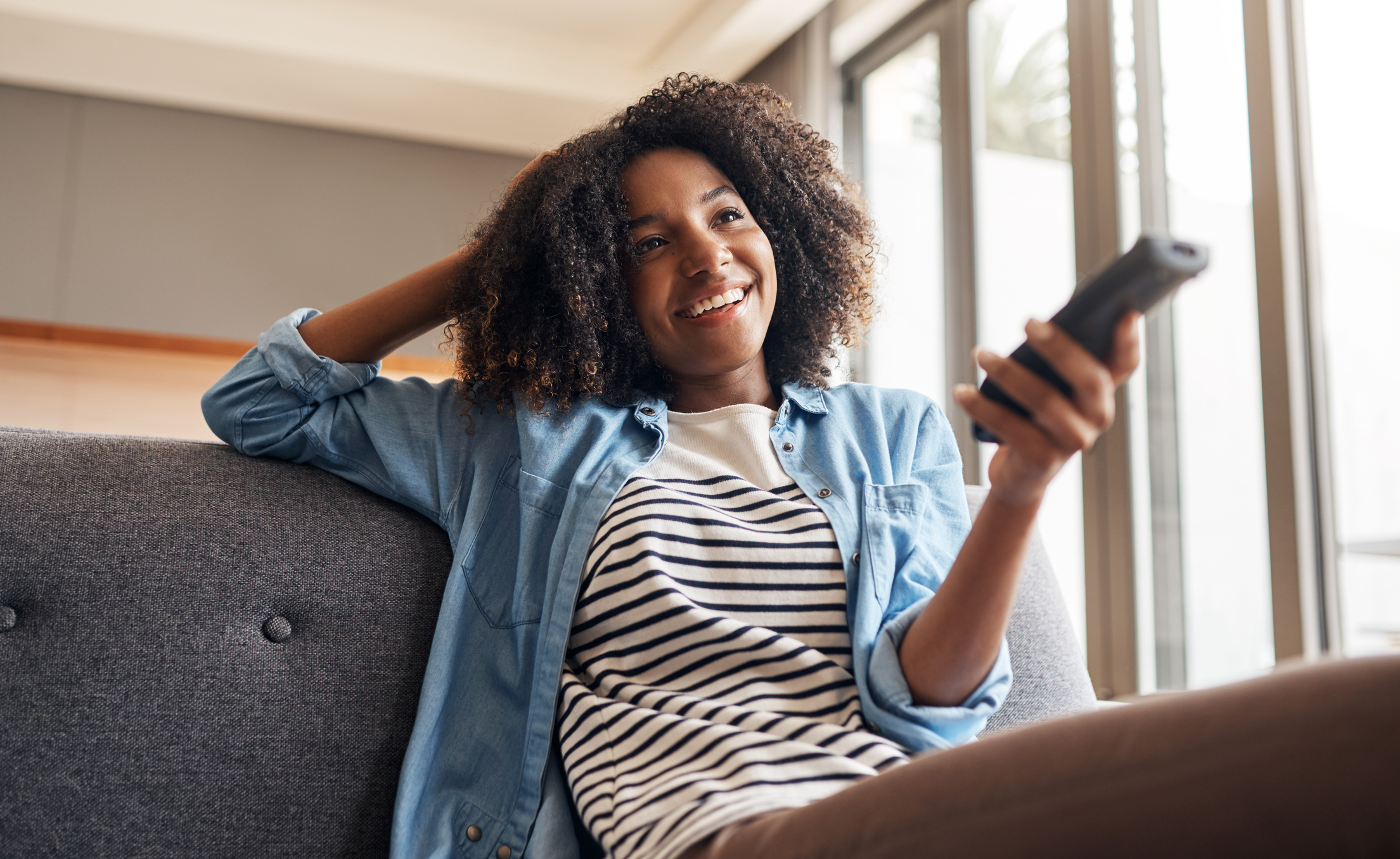 Someone smiling while channel surfing from a couch.