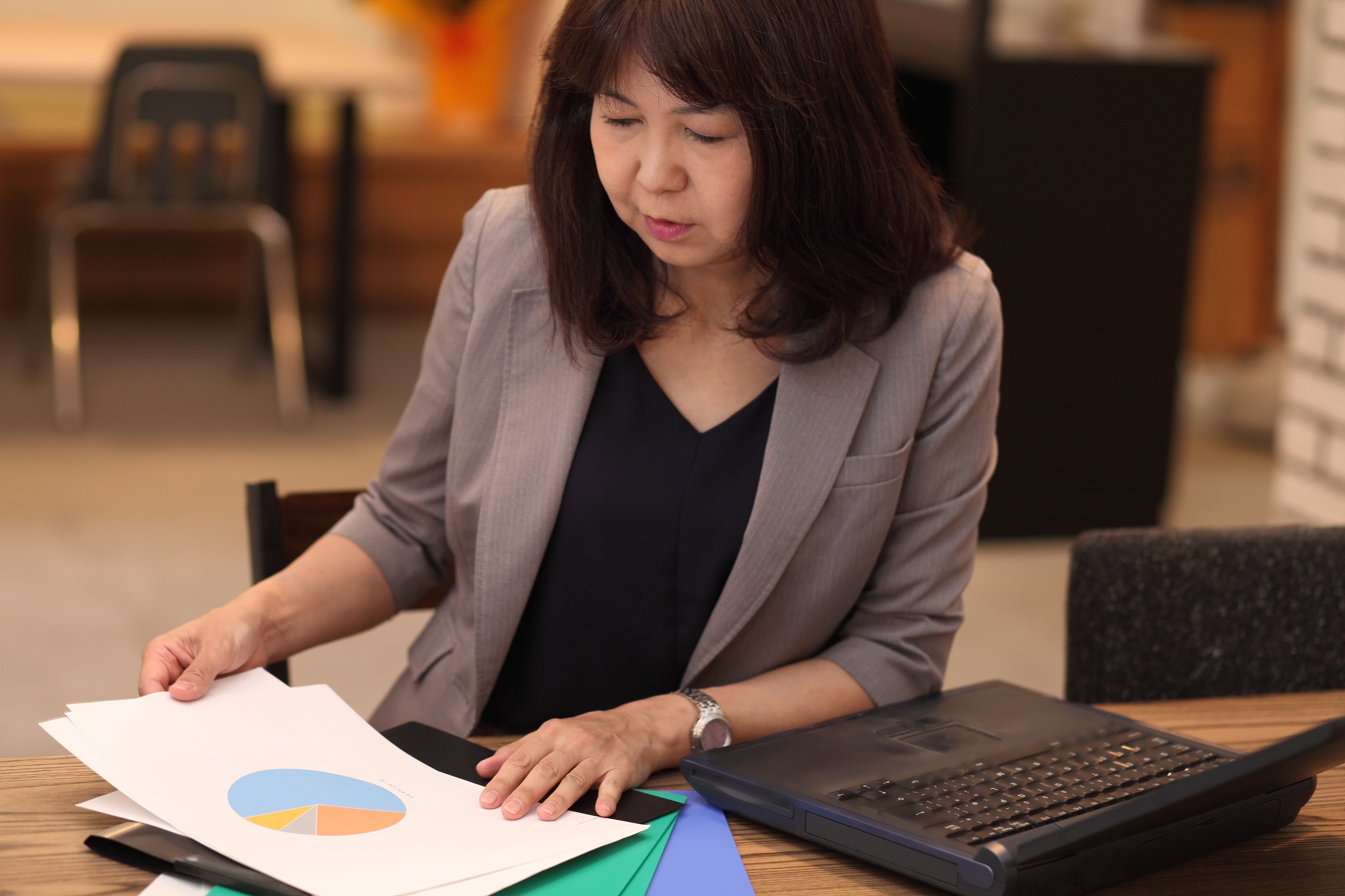 Person studying financial documents and charts for investment research.