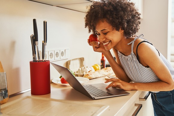 A smiling person looking at a laptop.