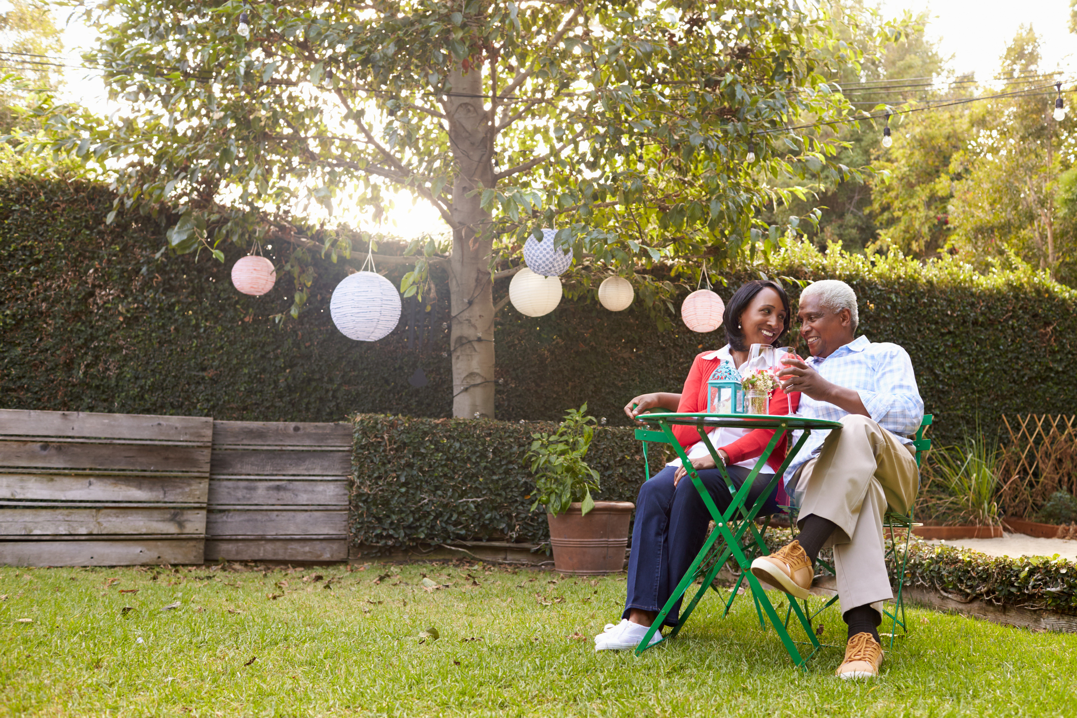 Two people drinking wine together in a backyard.