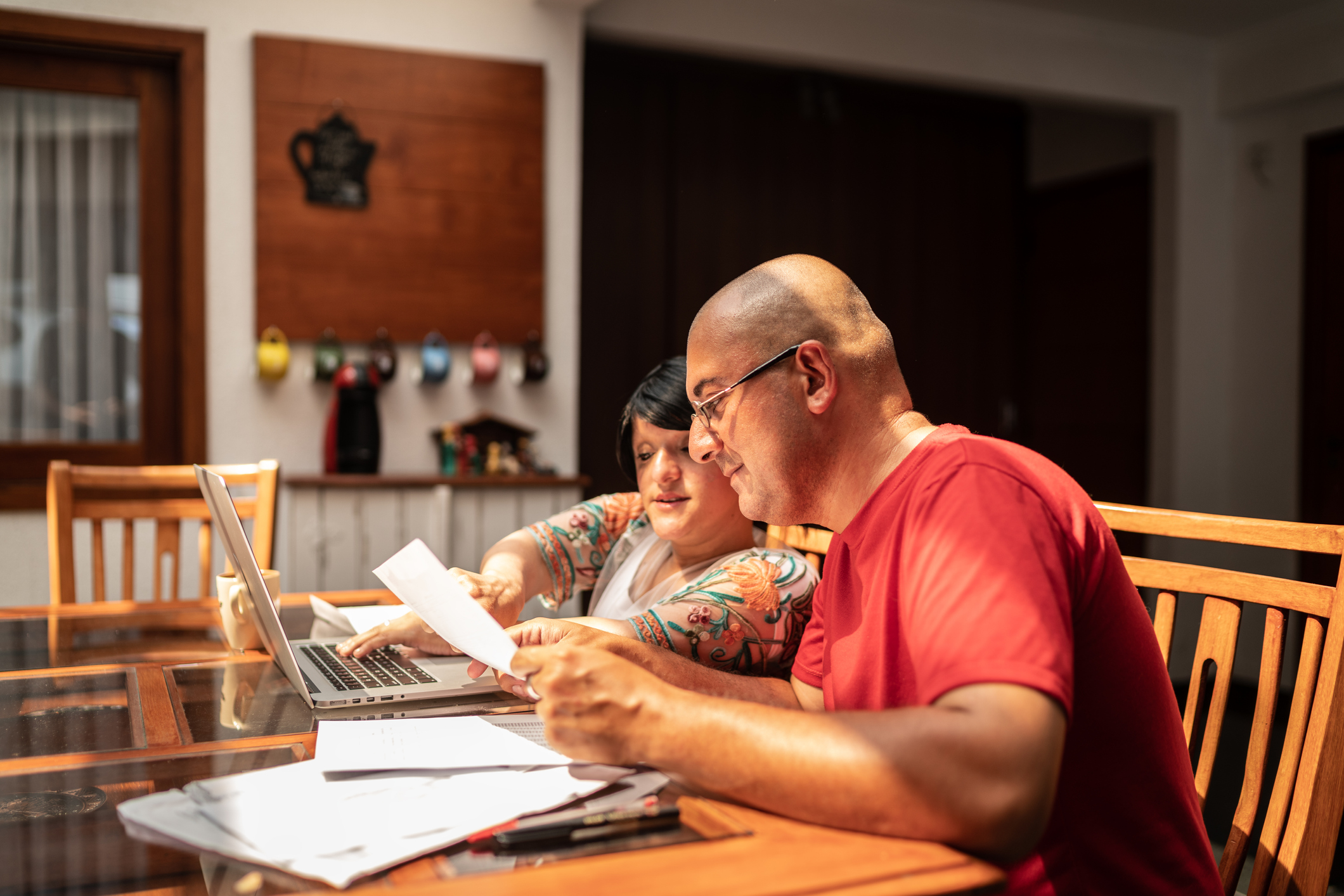 Two adults sitting at a table and looking at financial paperwork.