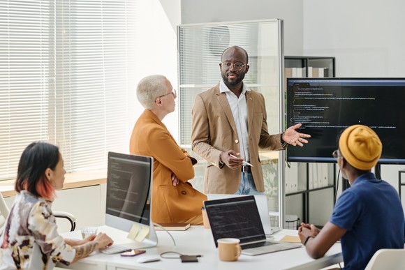 A team of people analyze software code in an office.