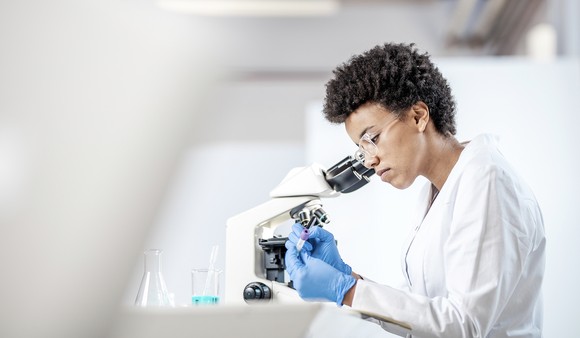 A scientist looking through a microscope.