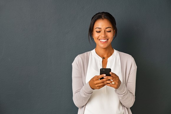 Person smiling while looking at a smartphone.