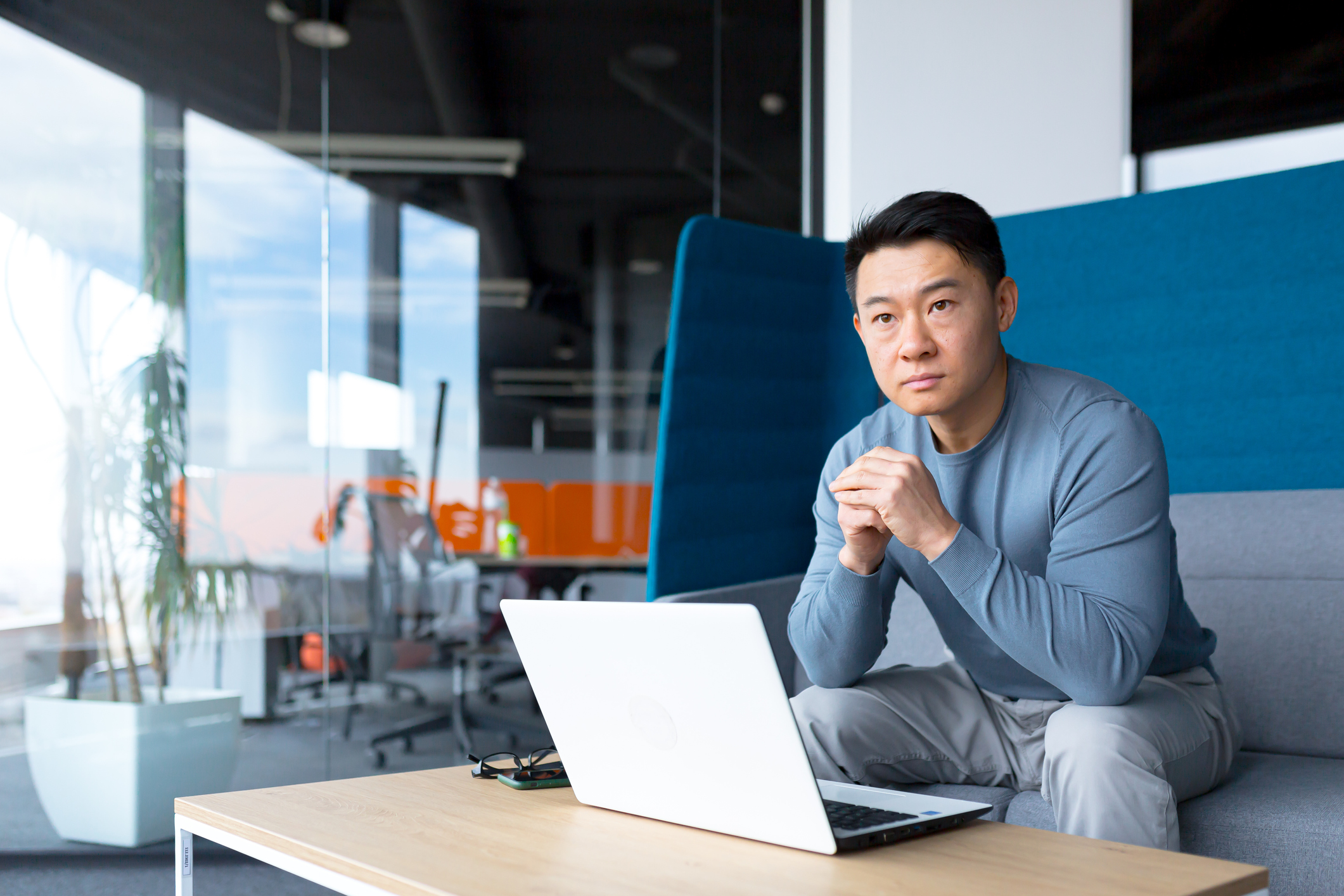 A person sitting on a couch in an office with a laptop in front of them.