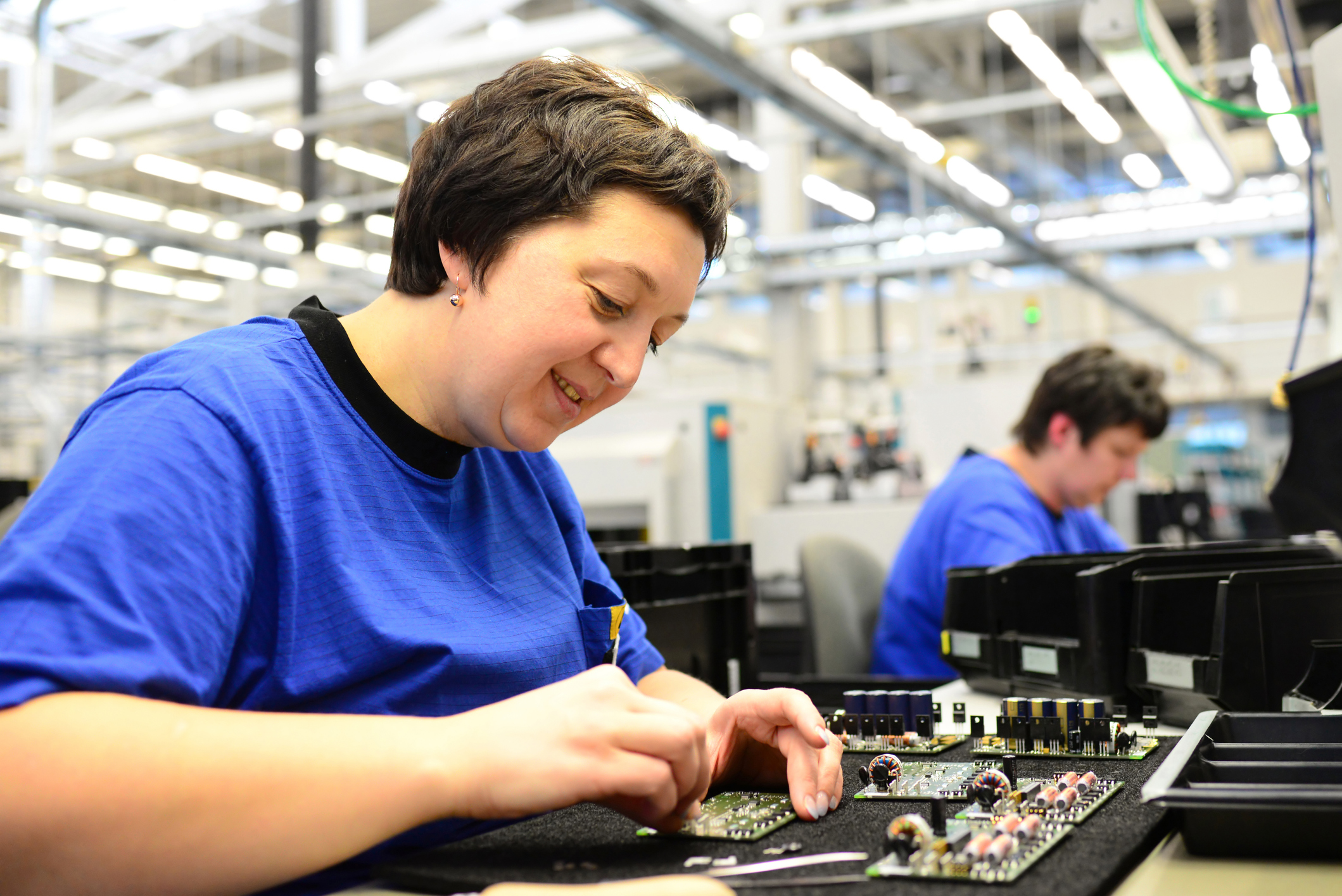 People in a factory assembling semiconductor components.