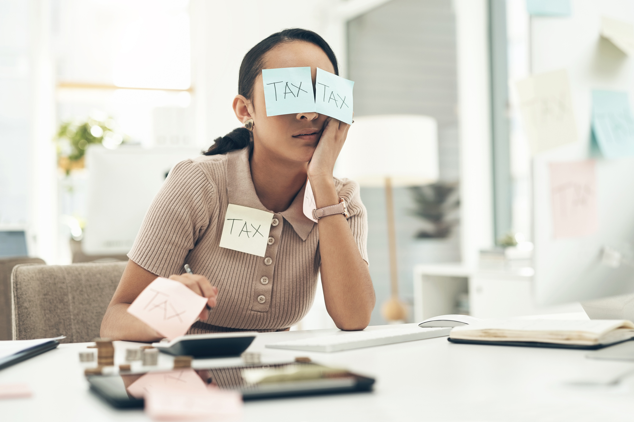 Someone sitting at a desk with sticky notes on them with the word "TAX."