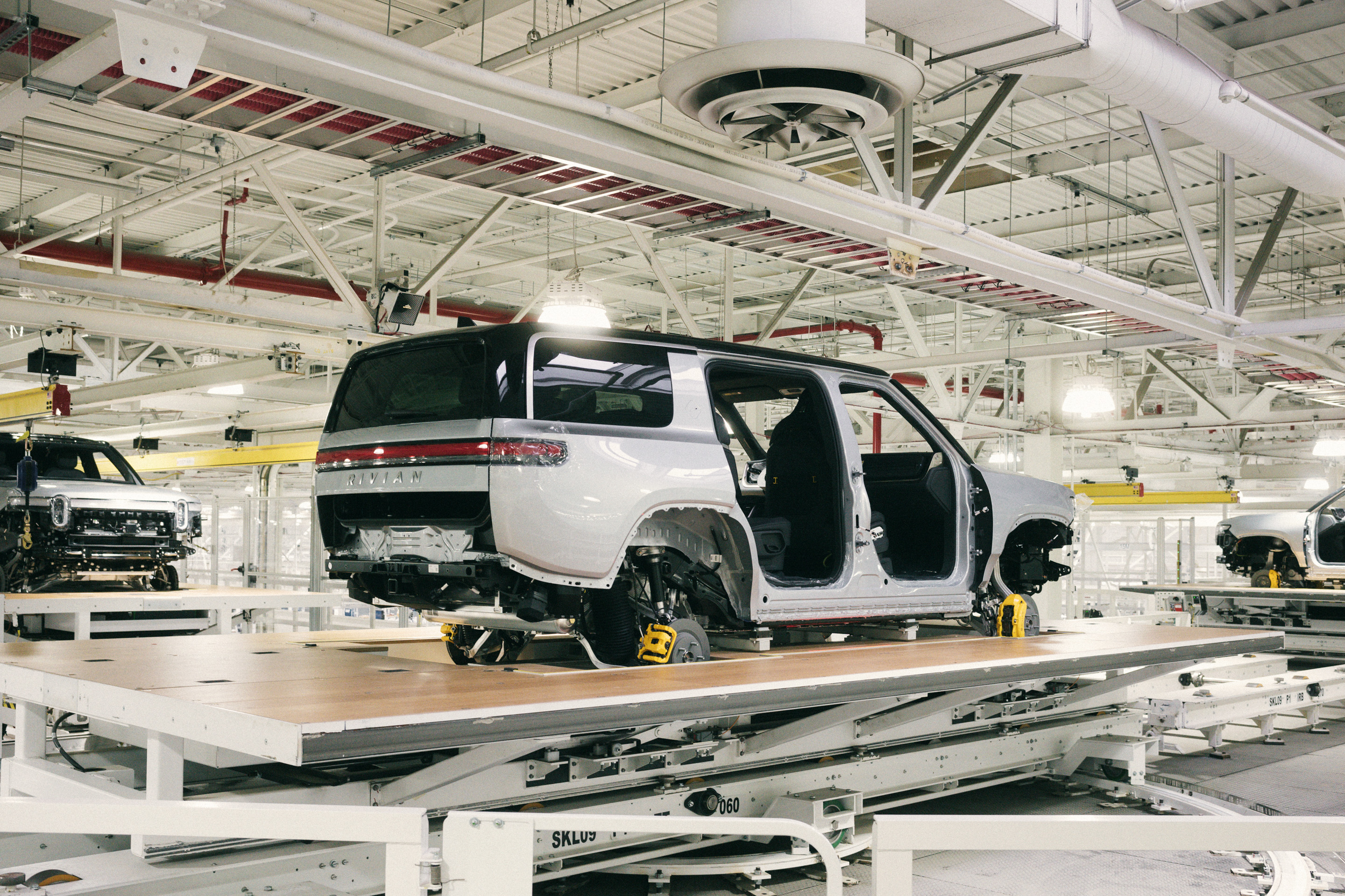 An all-electric Rivian R1S SUV being moved to a new station along the assembly line.