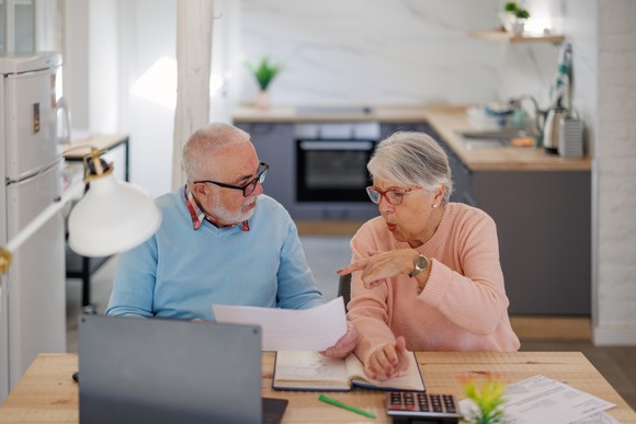 Two people at a desk with a laptop and documents.