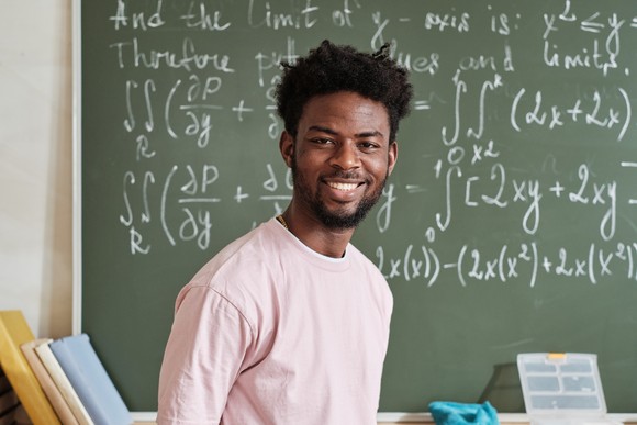 Someone standing in front of a chalkboard with math equations written on it.