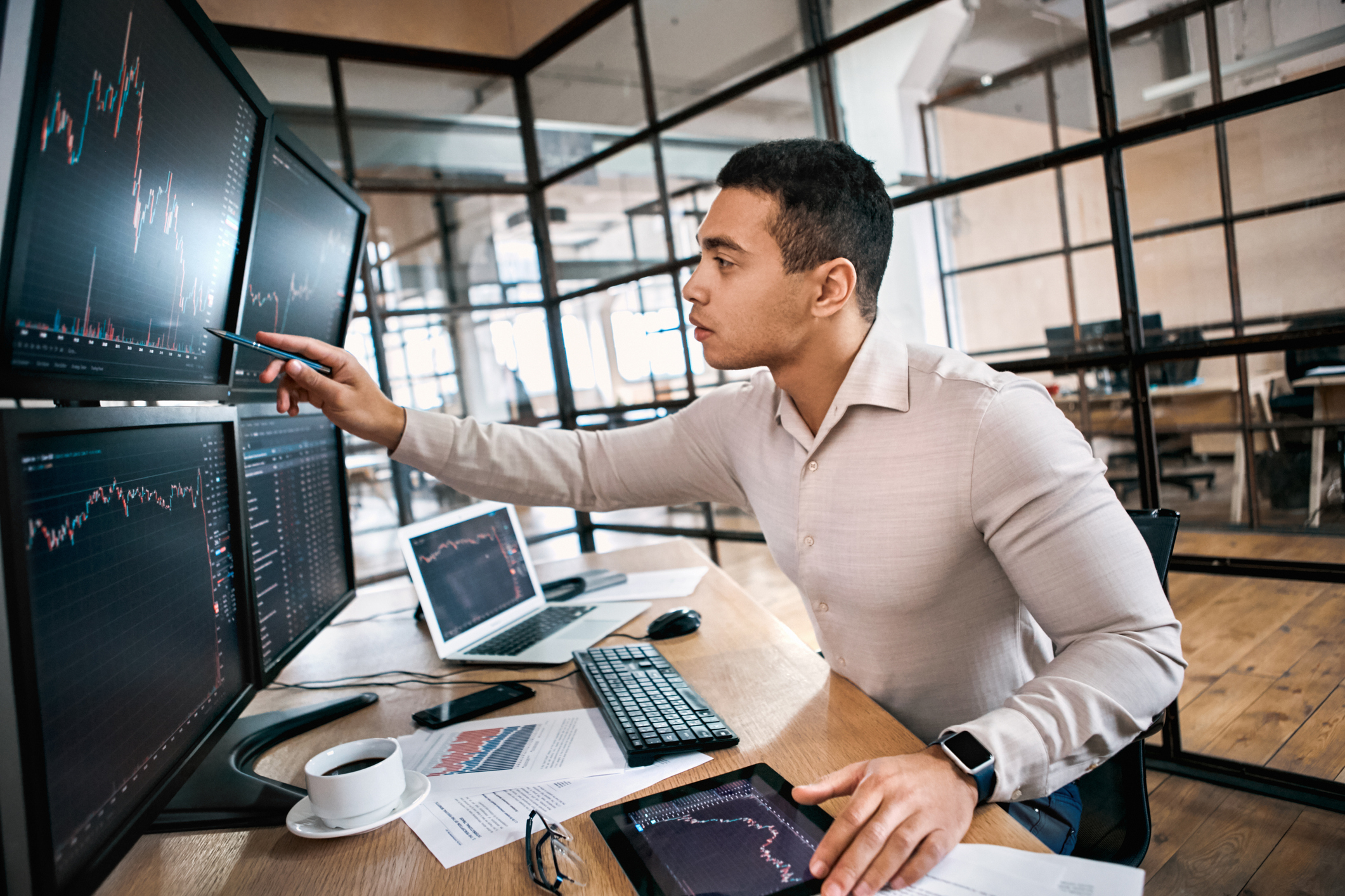 A stock analyst points a pen at a price chart displayed on a computer screen.