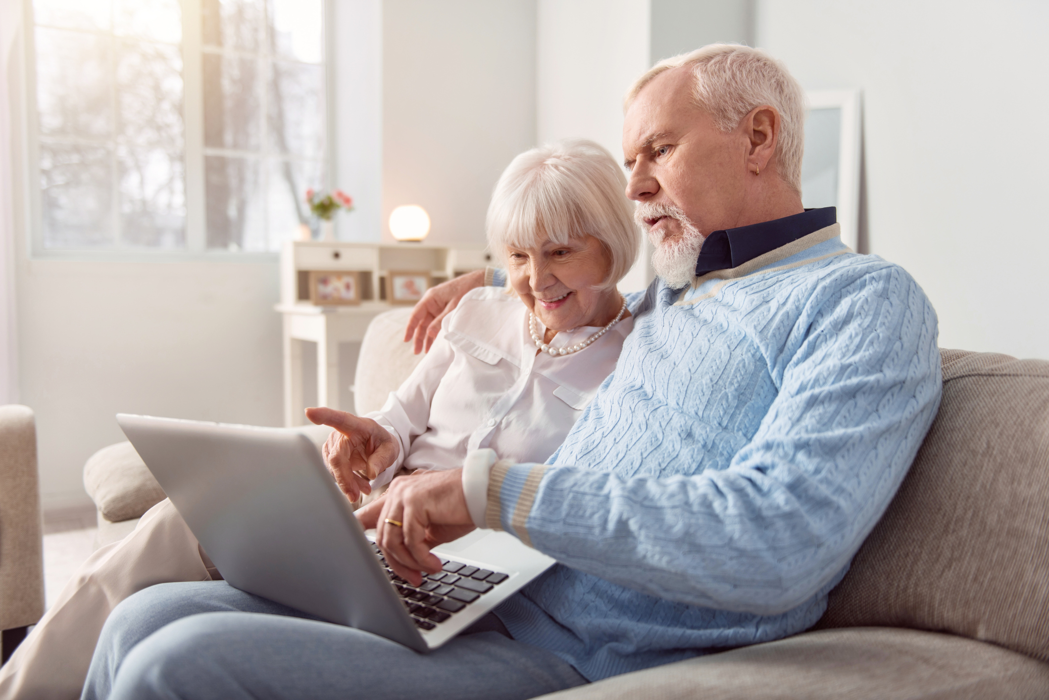 Two people looking at computer on couch.
