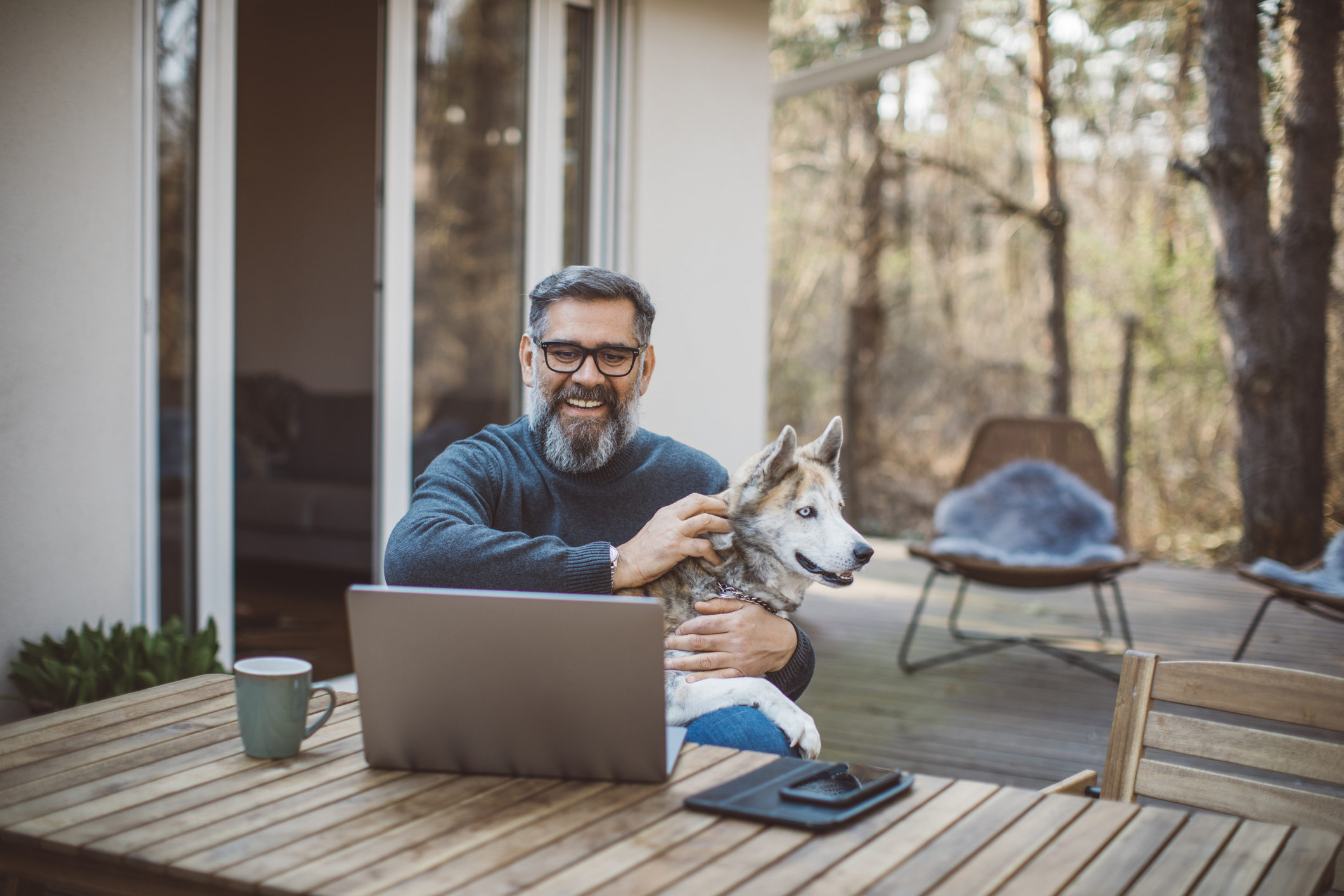 A person outside at a laptop holding a dog.
