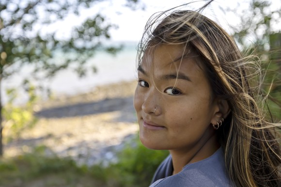 Person outside, looking at the camera and smiling slightly.