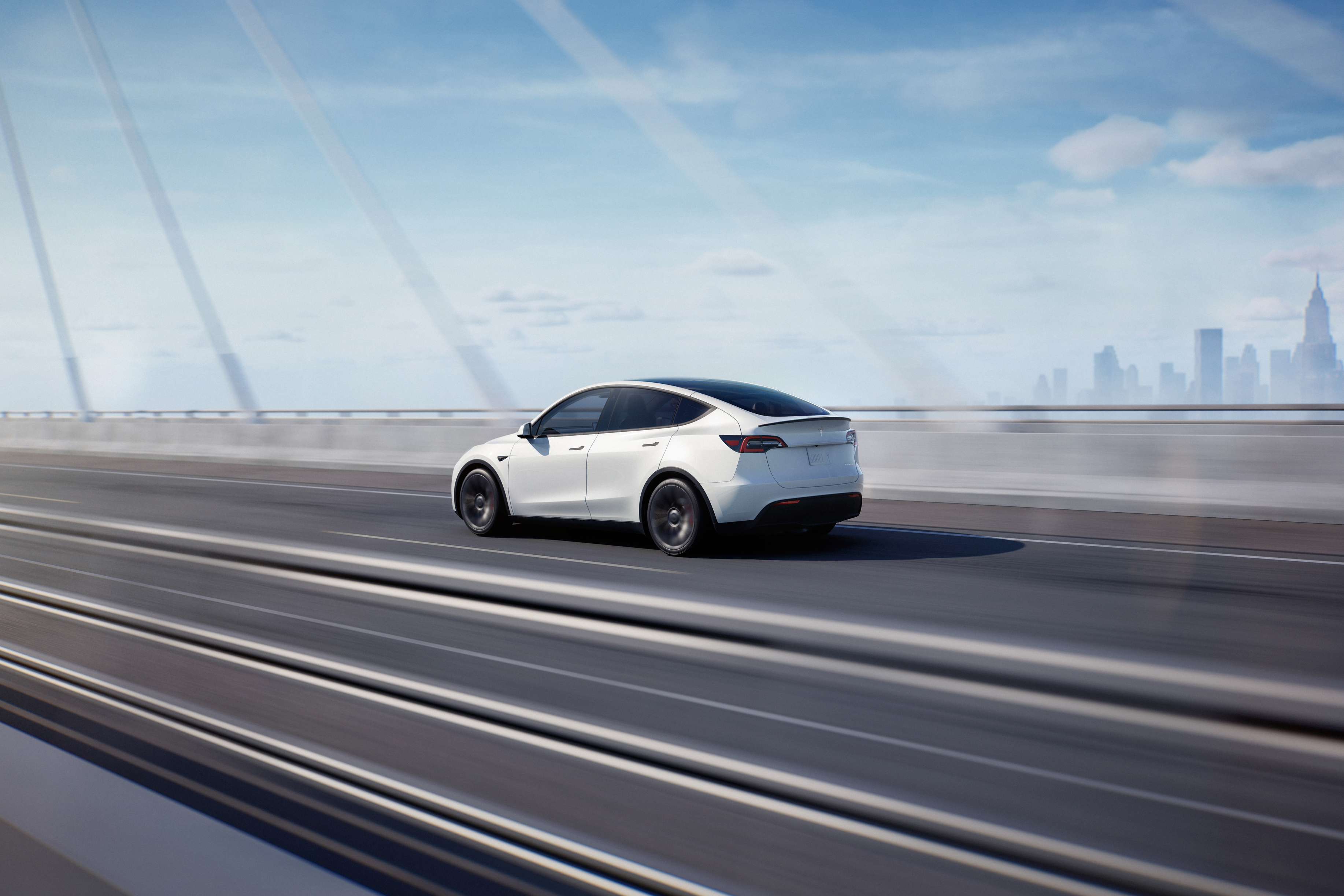 White Tesla Model Y traveling on a highway.