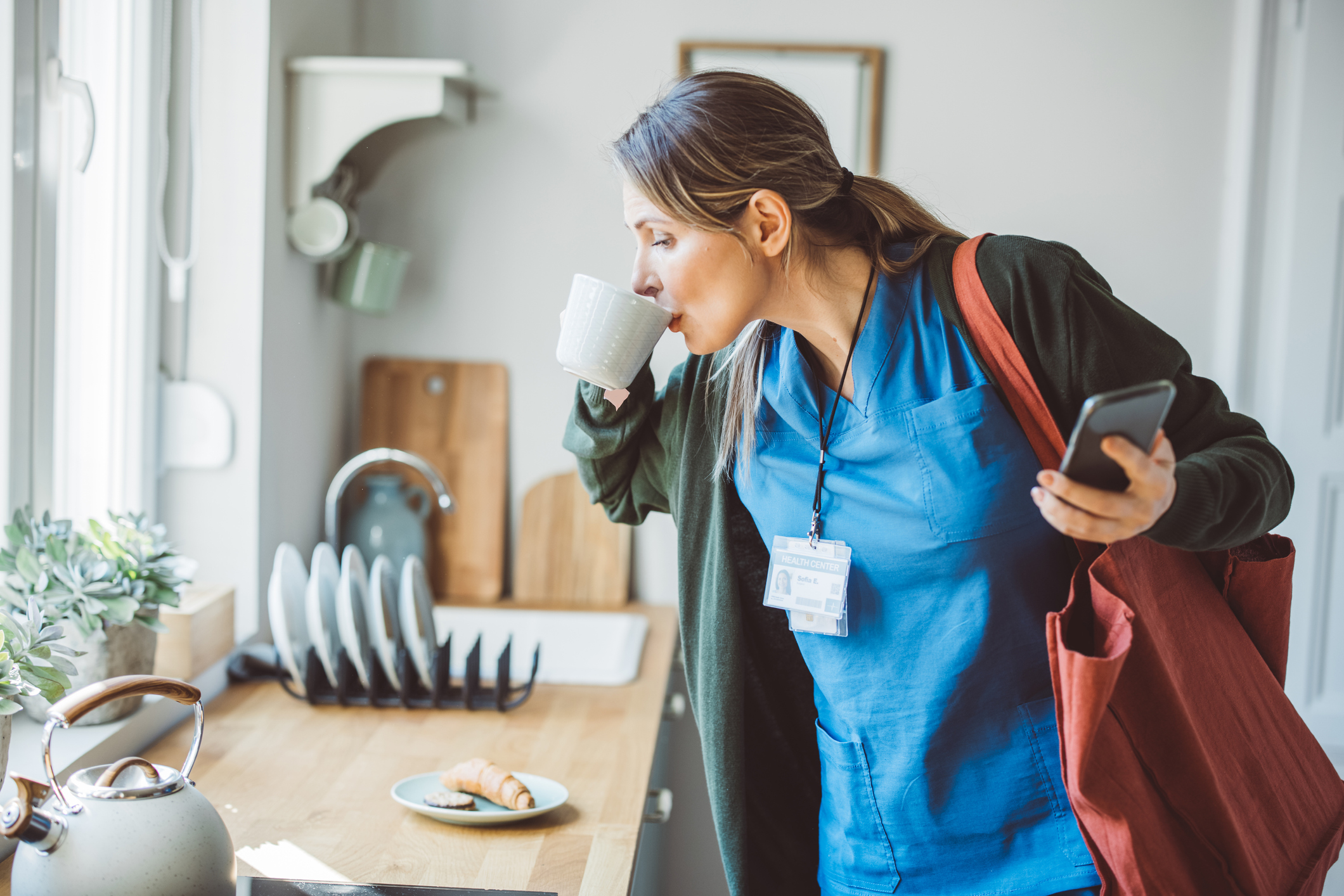 A person drinking coffee while standing over a table.