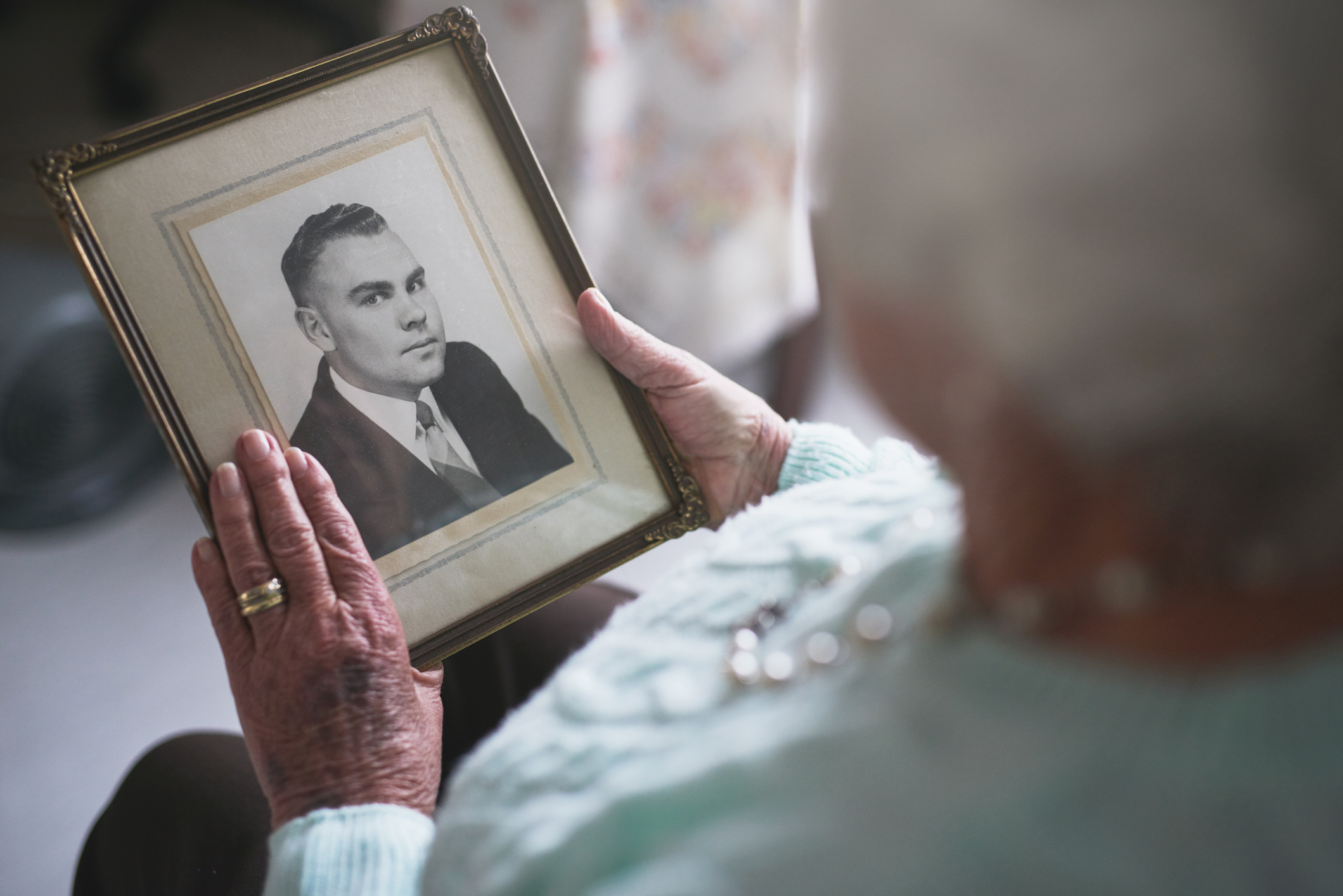 A person holding a black-and-white framed portrait.