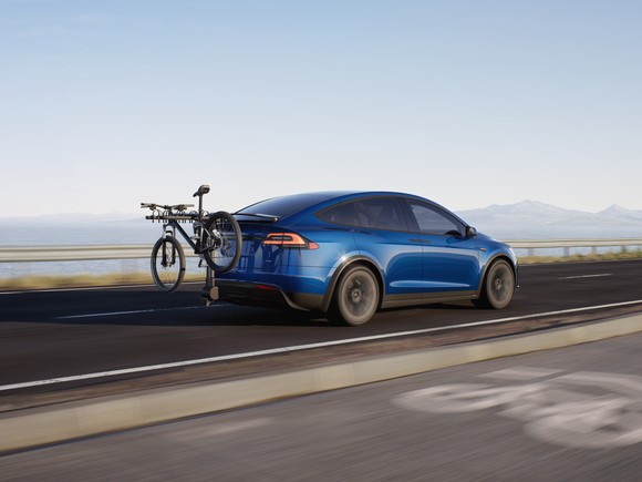 Blue Tesla Model X with bicycle on back rack. 