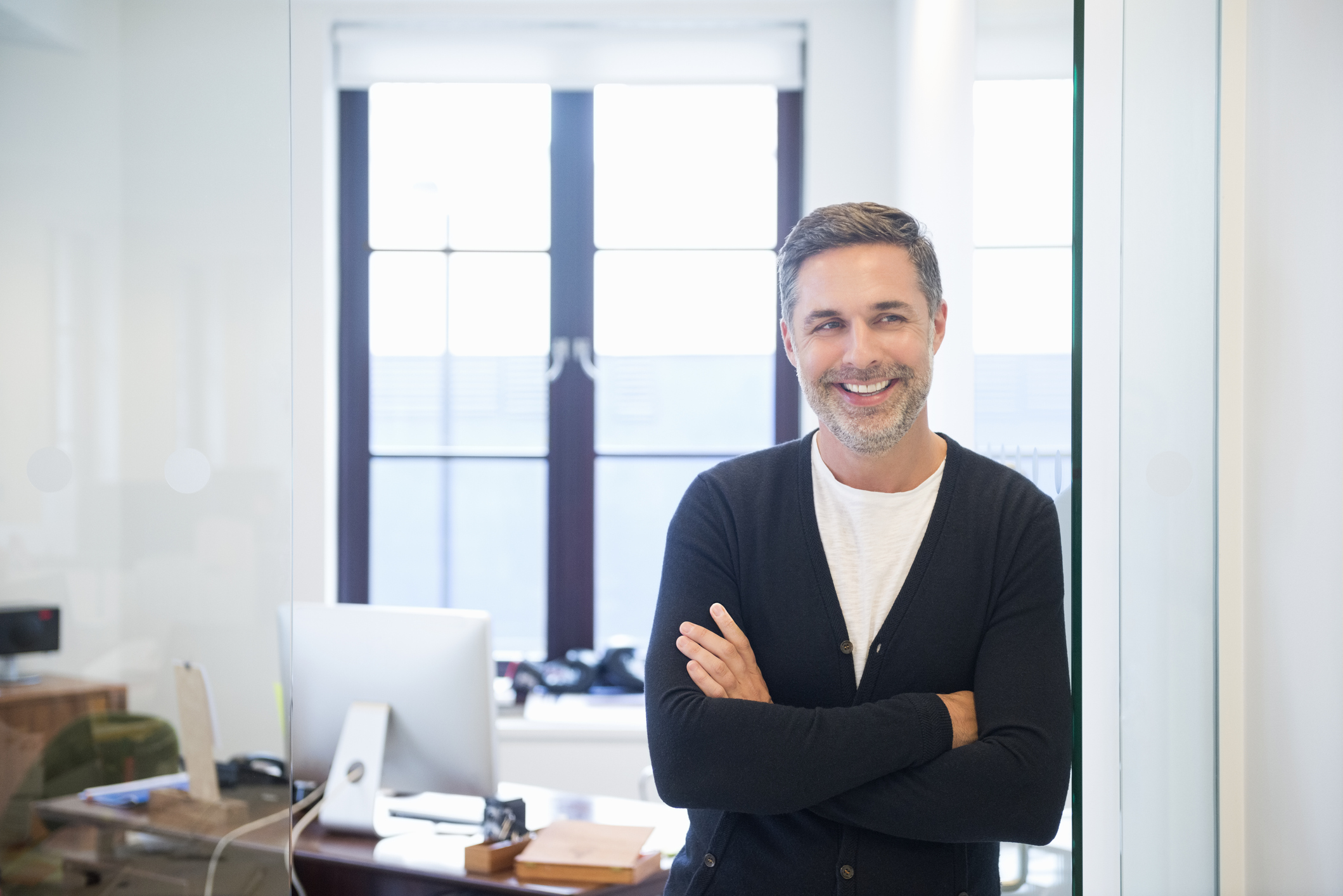 A smiling person in front of a desk.