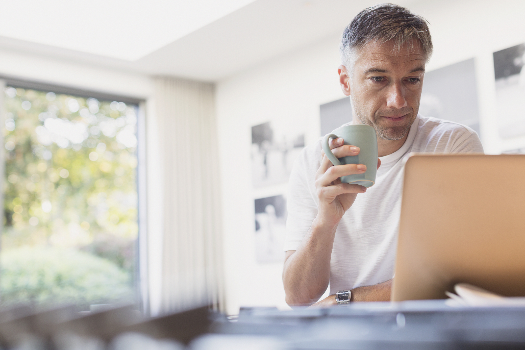 A person at a laptop holding a mug.