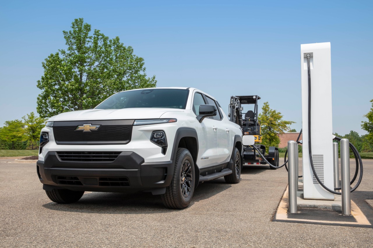 A 2024 Chevy Silverado EV with attached trailer parked at an EV charging station.