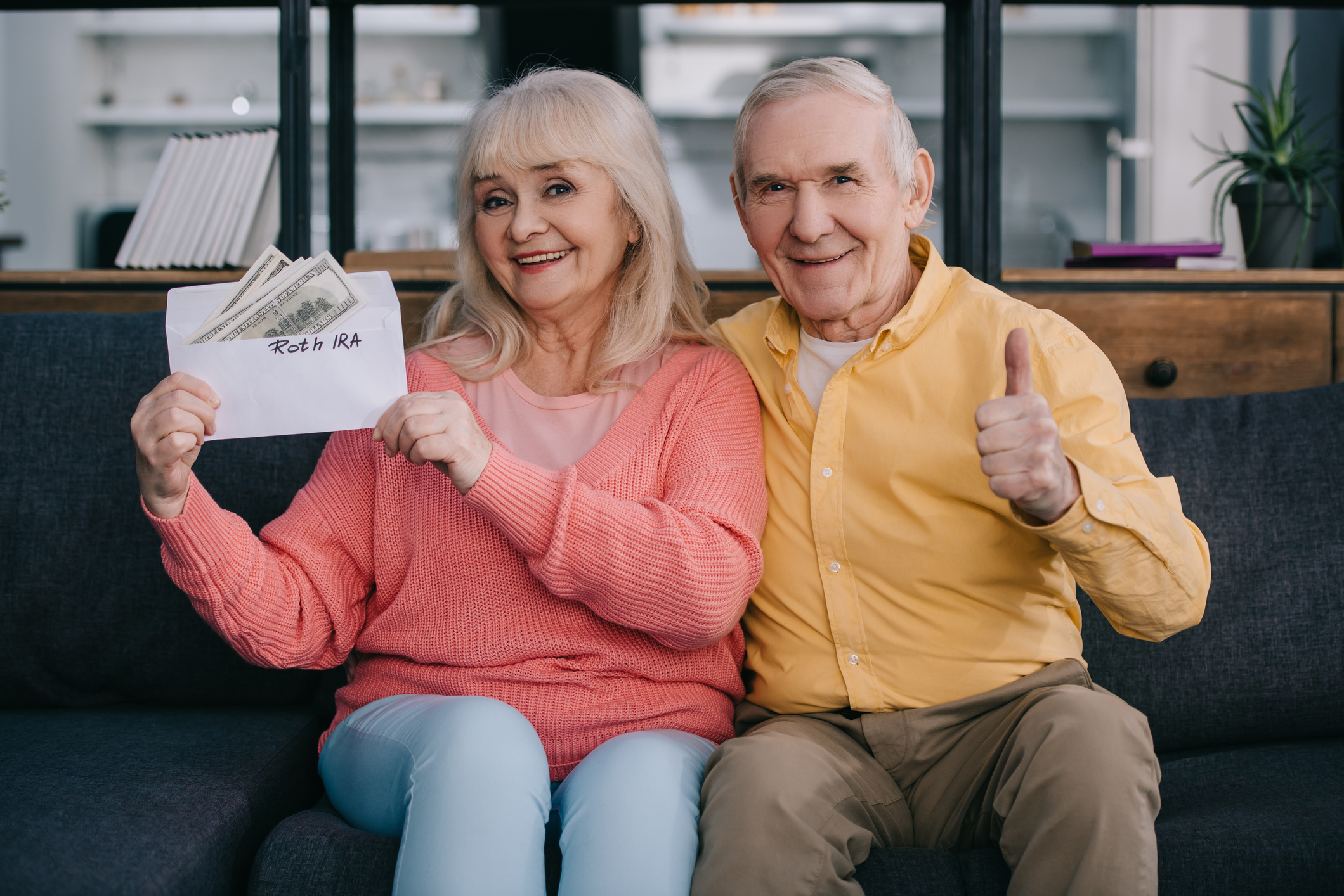 Two people sitting together holding cash and a thumbs-up.