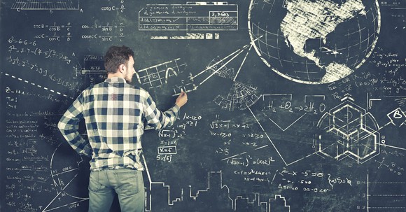 Man draws mathematical calculations and a world globe on a chalkboard.