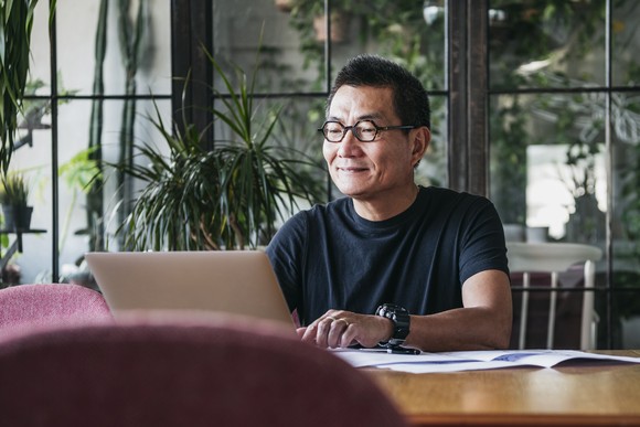 A person sits at a table and works on a laptop.
