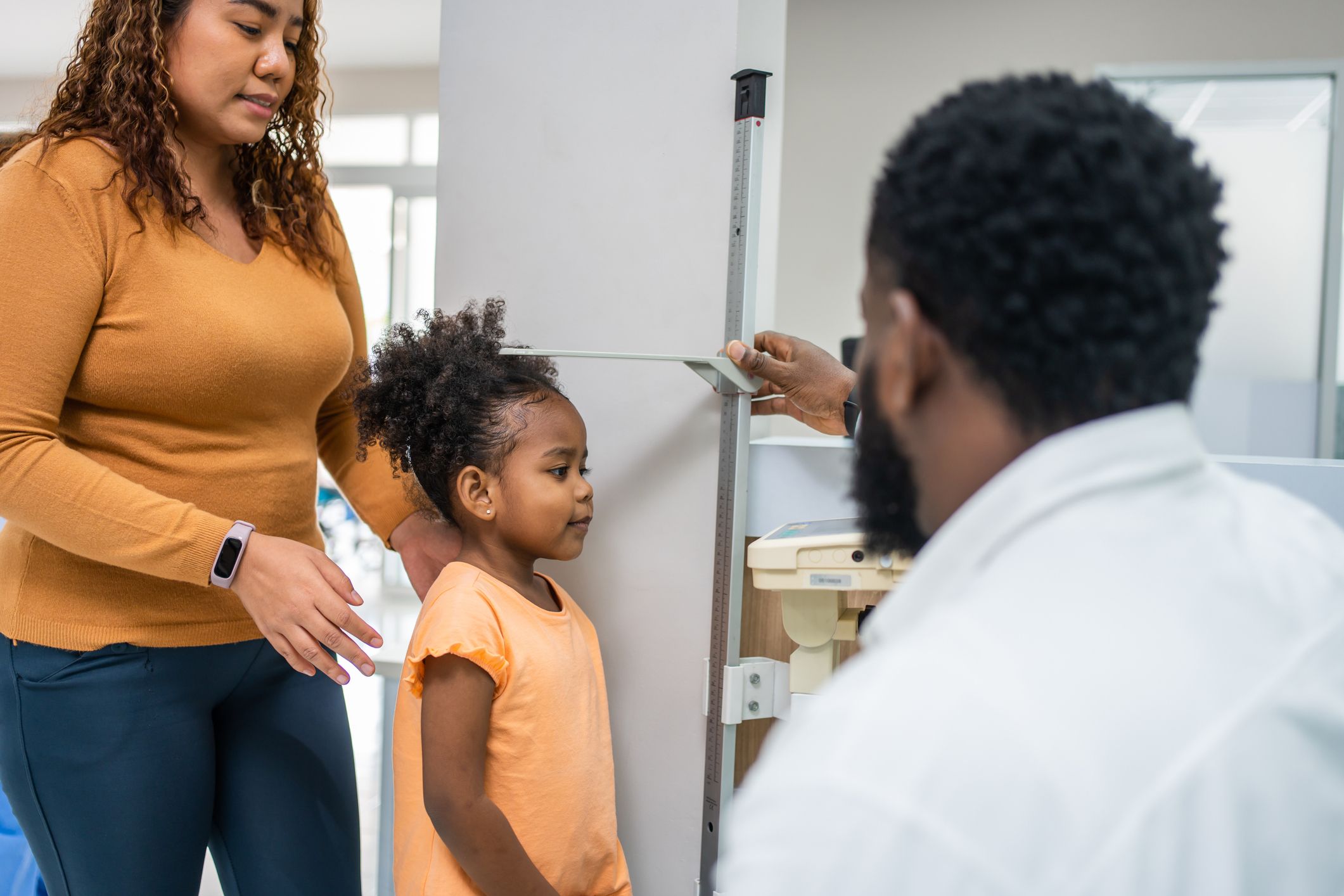 A person measuring a child's height in an office.