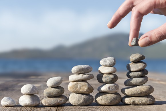 Hand stacking stones in increasingly taller towers.