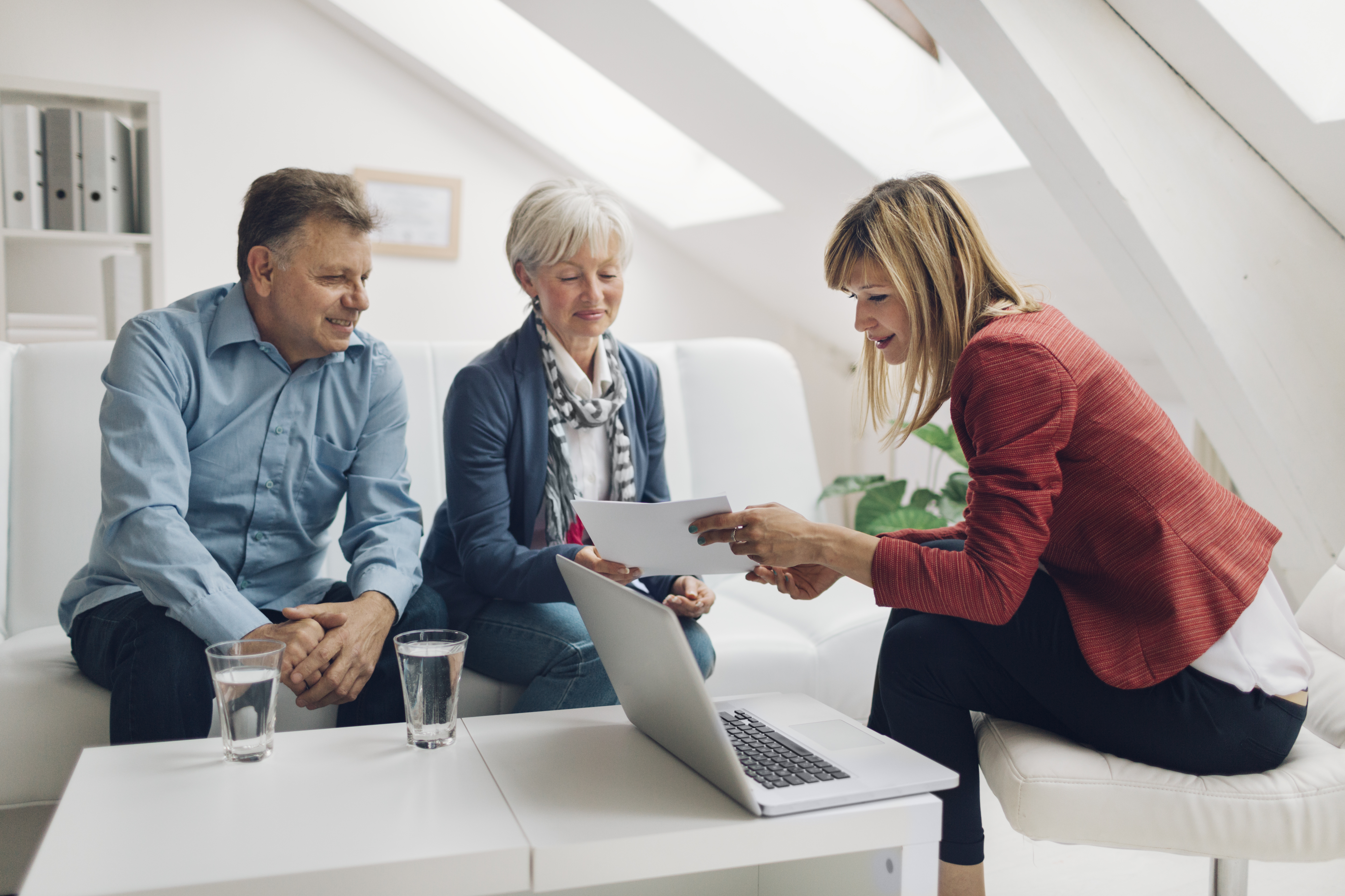 A person hands documents to another person in an office.