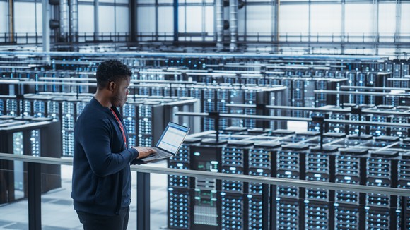 Data center engineer using laptop at cryptocurrency mining facility.
