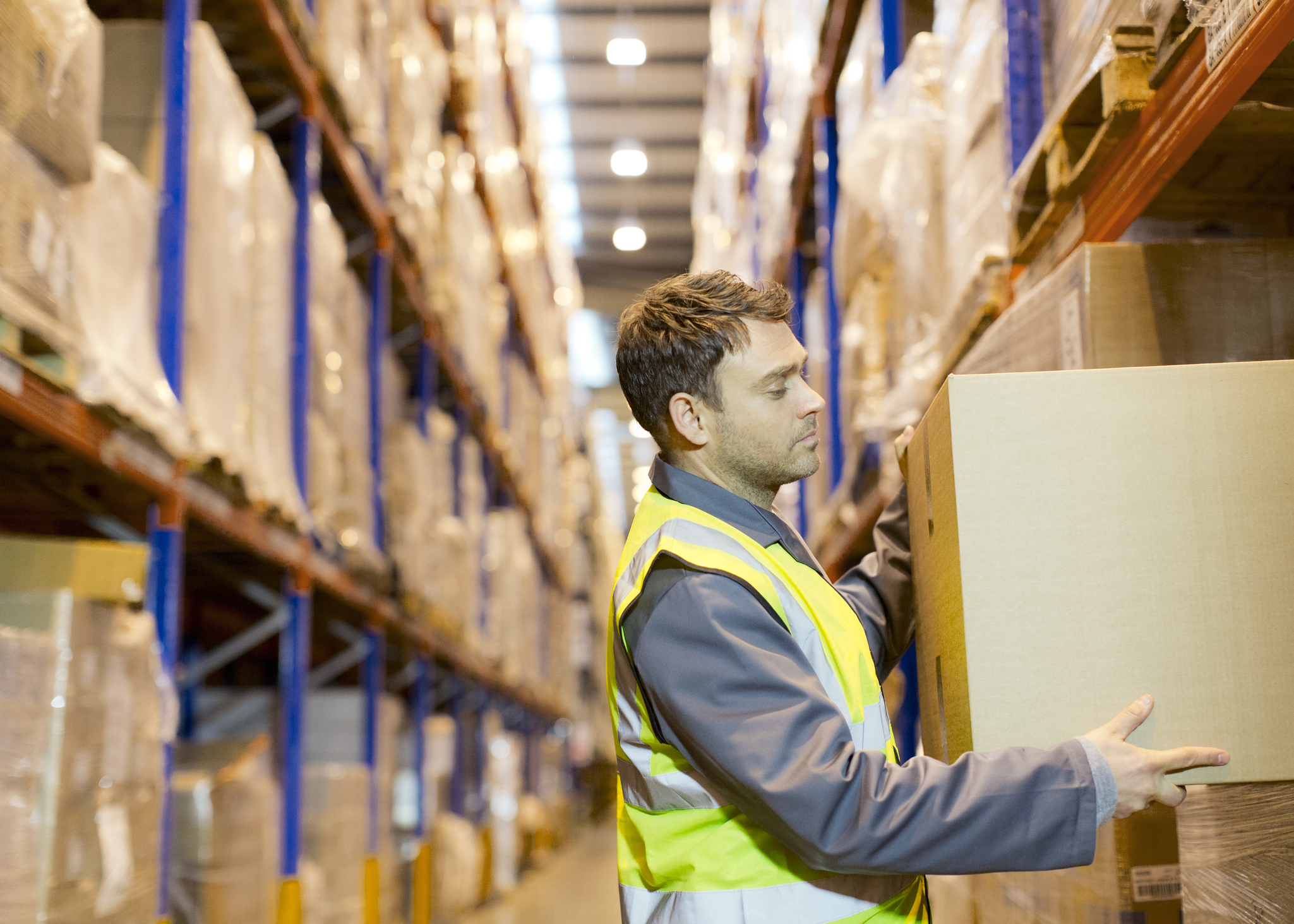 A person lifting a box in a warehouse.