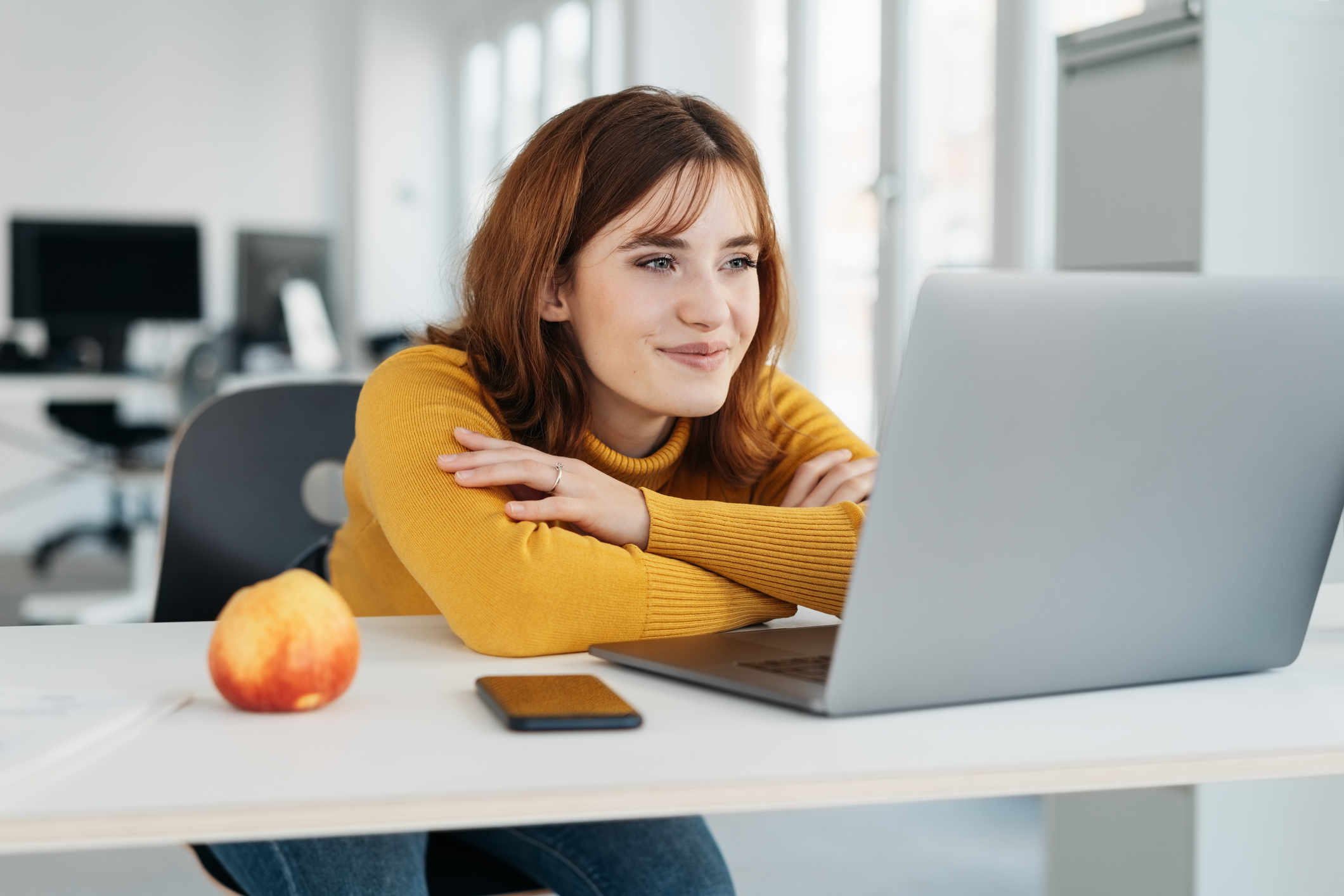 Woman 20s yellow shirt laptop smiling GettyImages-1224413248