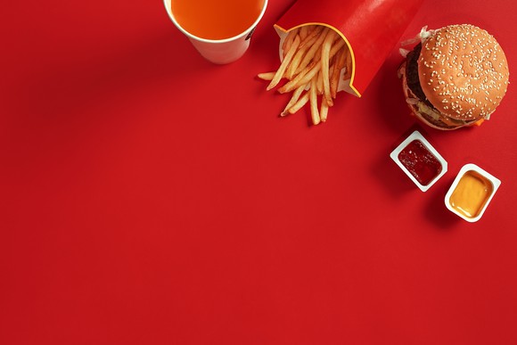 A hamburger, fries and a soft drink on a red table.