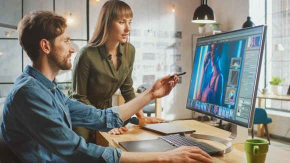 Two graphic designers edit a photo on a PC.