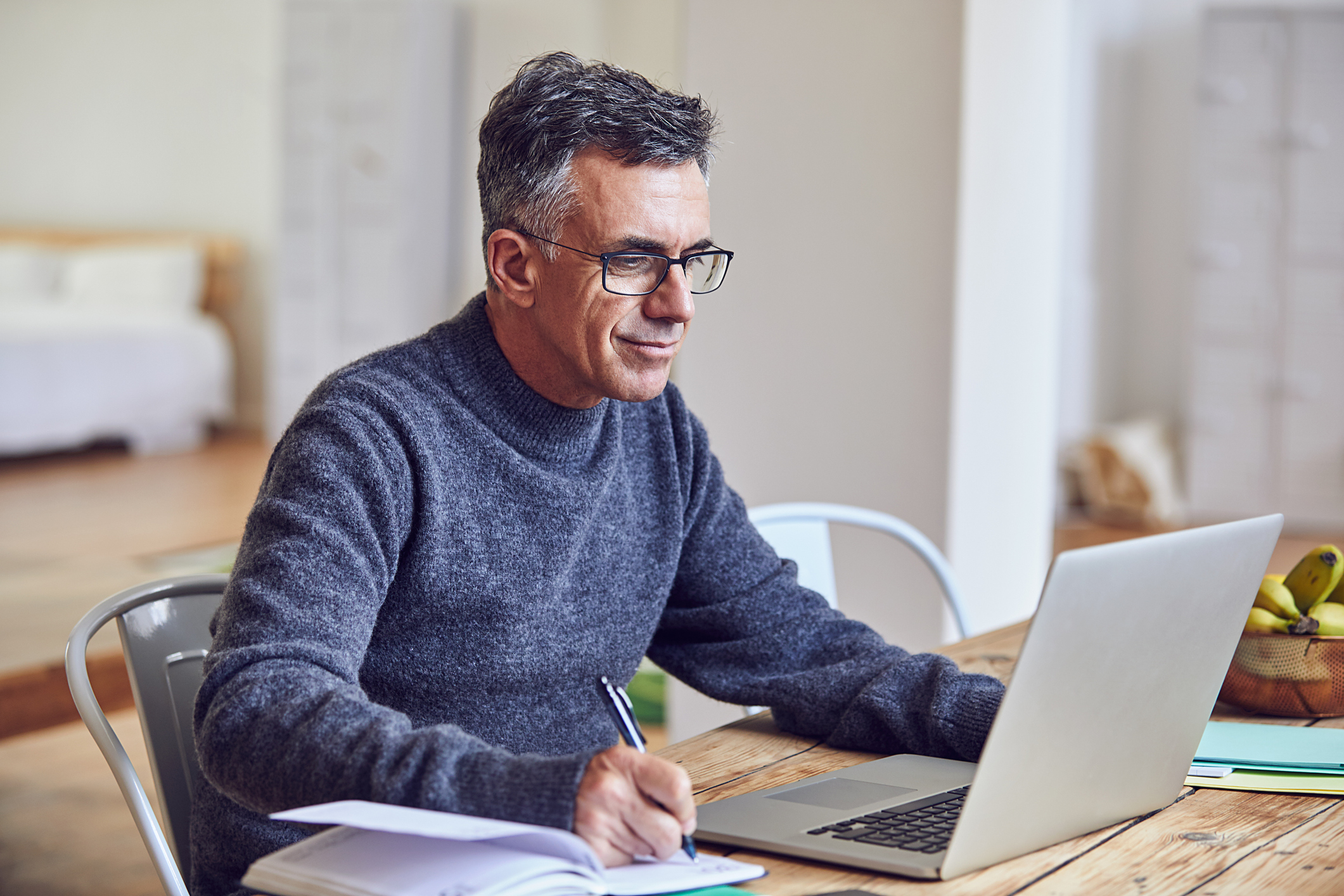 A person taking notes at a laptop.